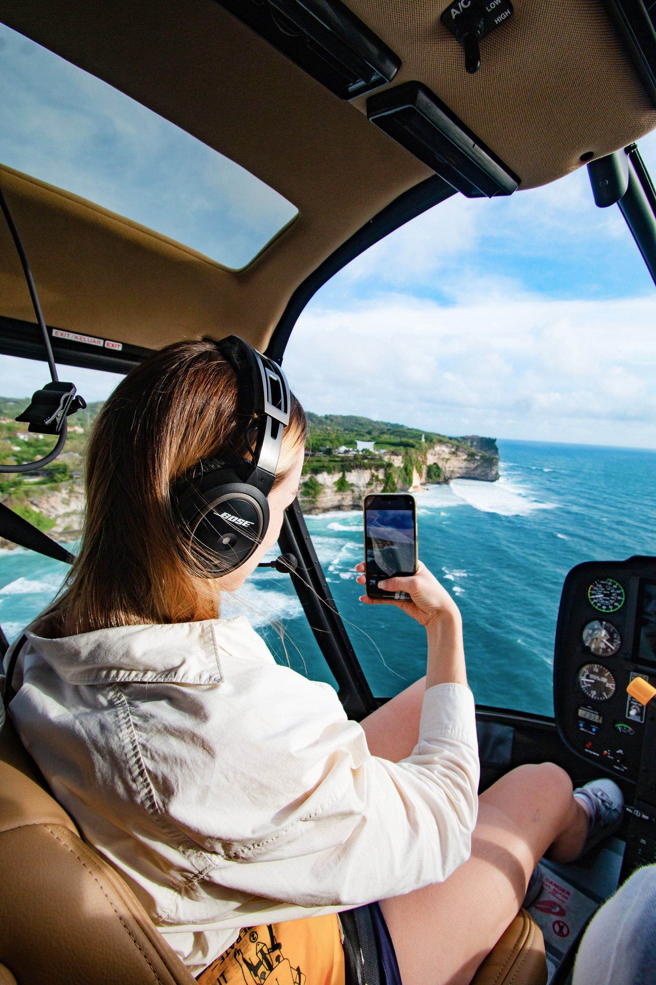A guest photographing the Bali coastline from the helicopter cabin